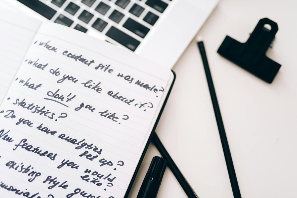 A close-up view of a notebook with handwritten notes alongside a laptop for planning and strategy.